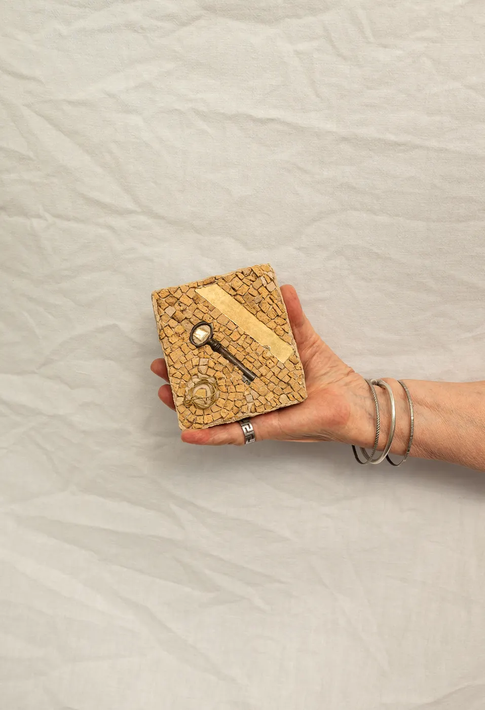 Une petite mosaïque ornée d'une clé, tenue à la main