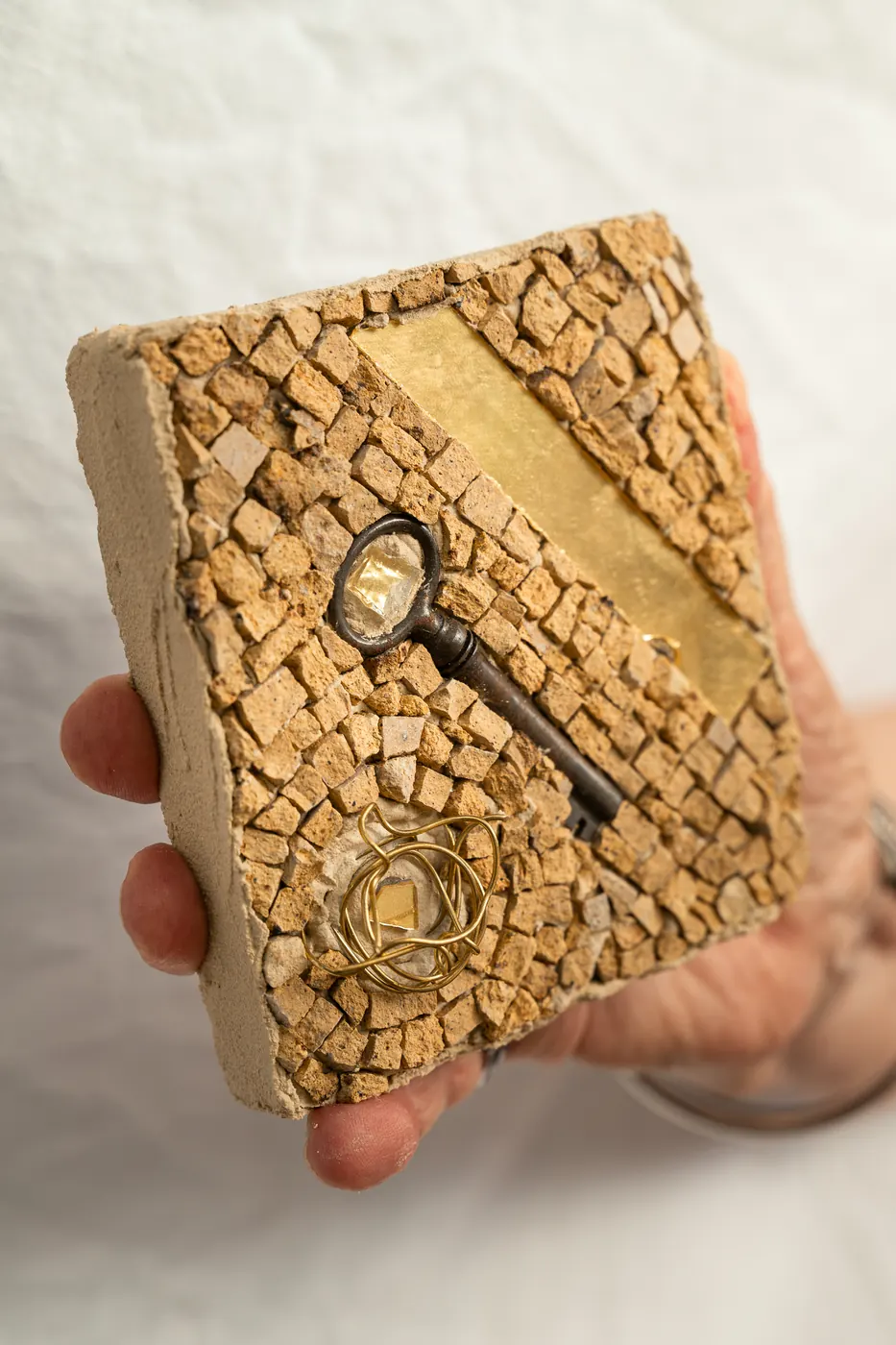 Petite mosaïque de terres cuites et d'une clé, présentée dans la main