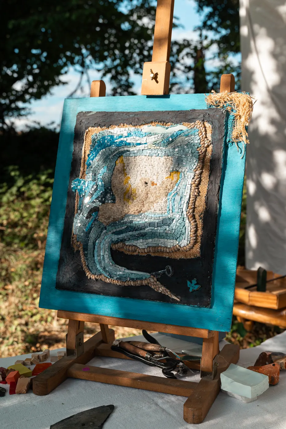 Un portrait en mosaïque sur son chevalet, cadre bleu profond