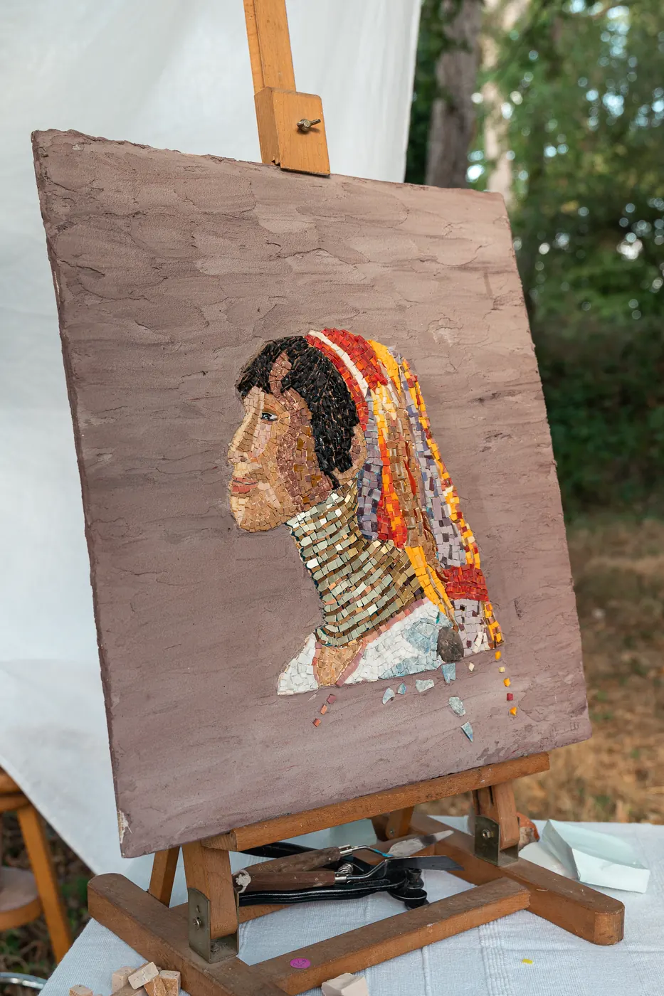 Portrait de femme en mosaïque, posé sur un chevalet dehors