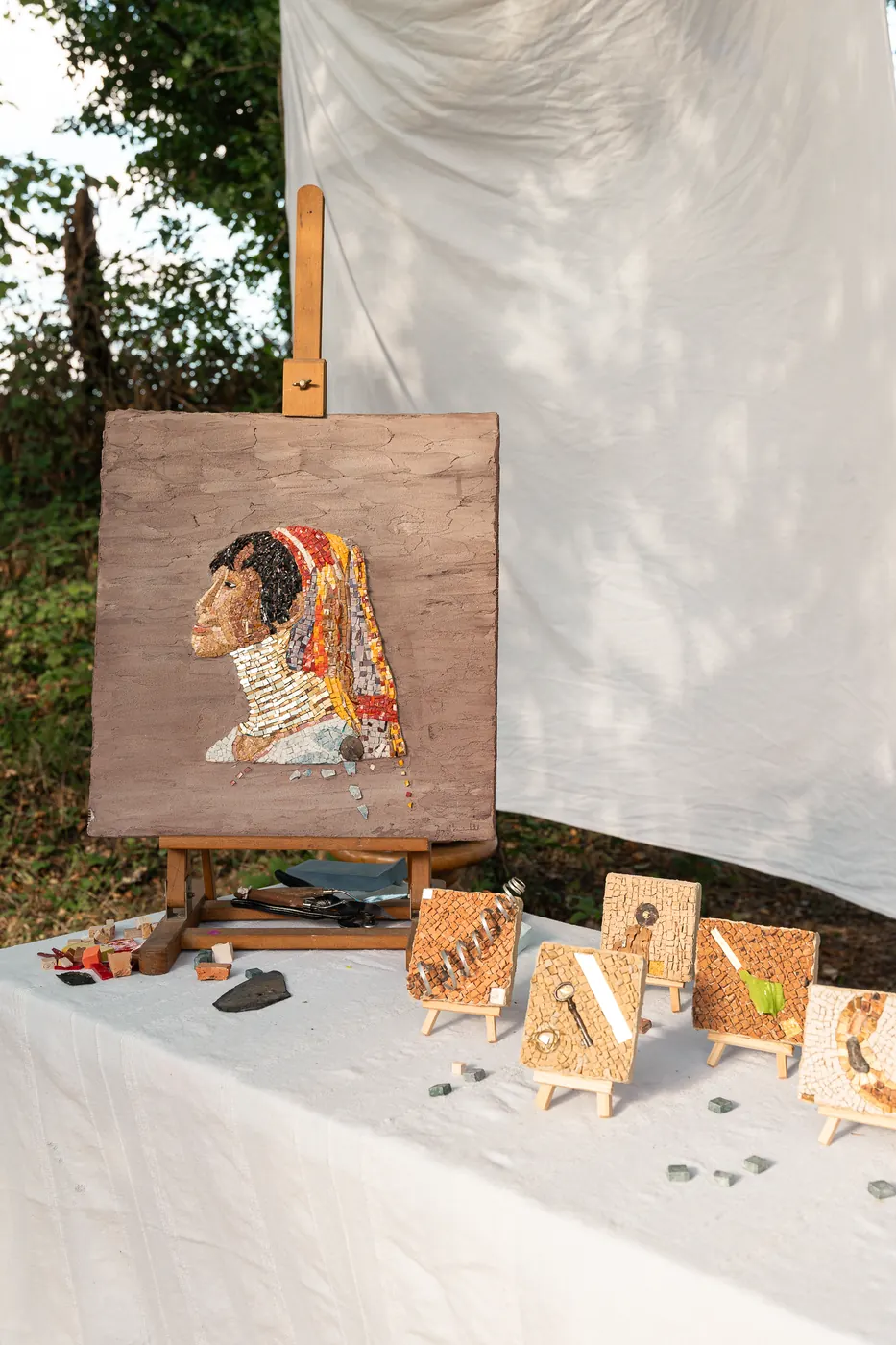 Le portrait en mosaïque sur son chevalet, entouré de petites pièces