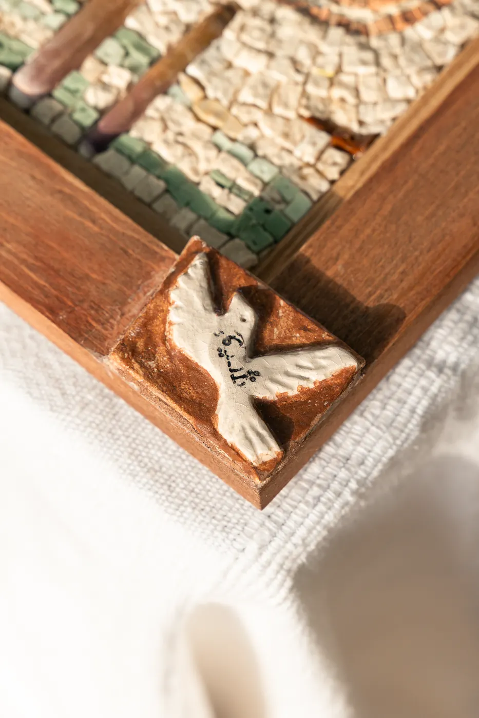 Détail d'une mosaïque encadrée de bois, oiseau blanc sur fond clair