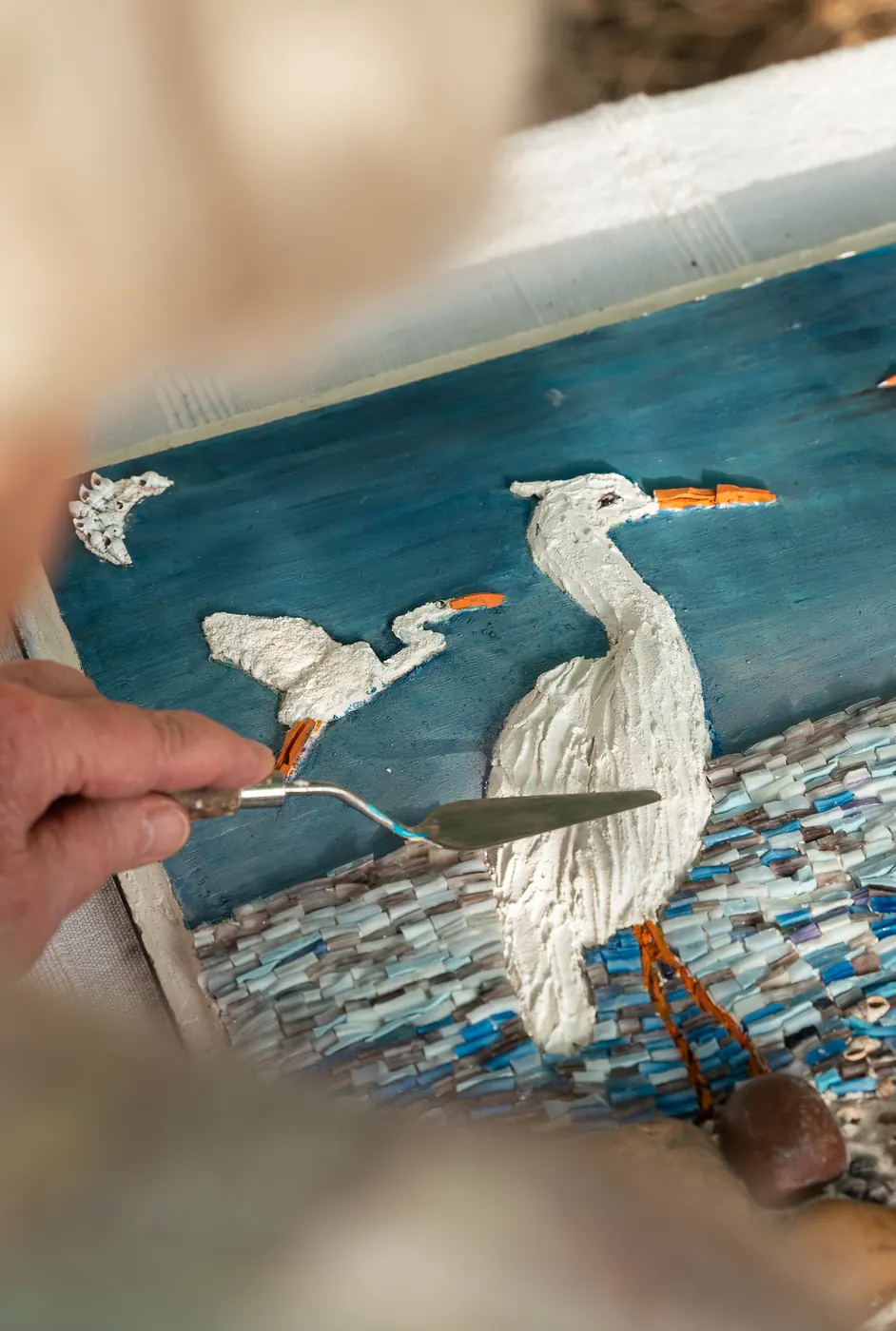 Travail à la spatule sur une mosaïque représentant une aigrette