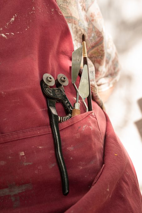 Pinces et spatules dans la poche du tablier d'atelier